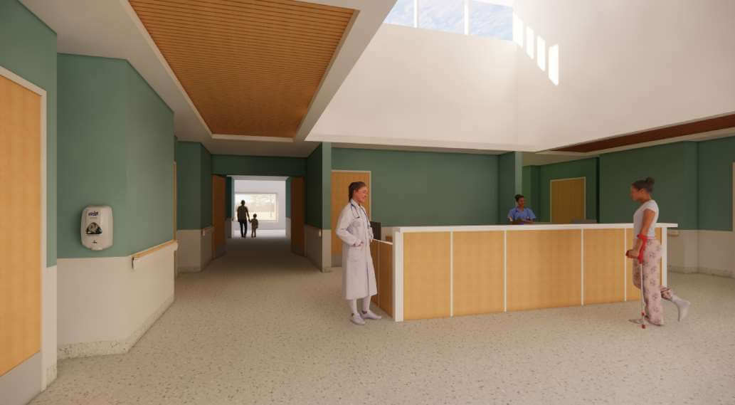 Nursing care stations with brown wood, green walls and one health care worker.